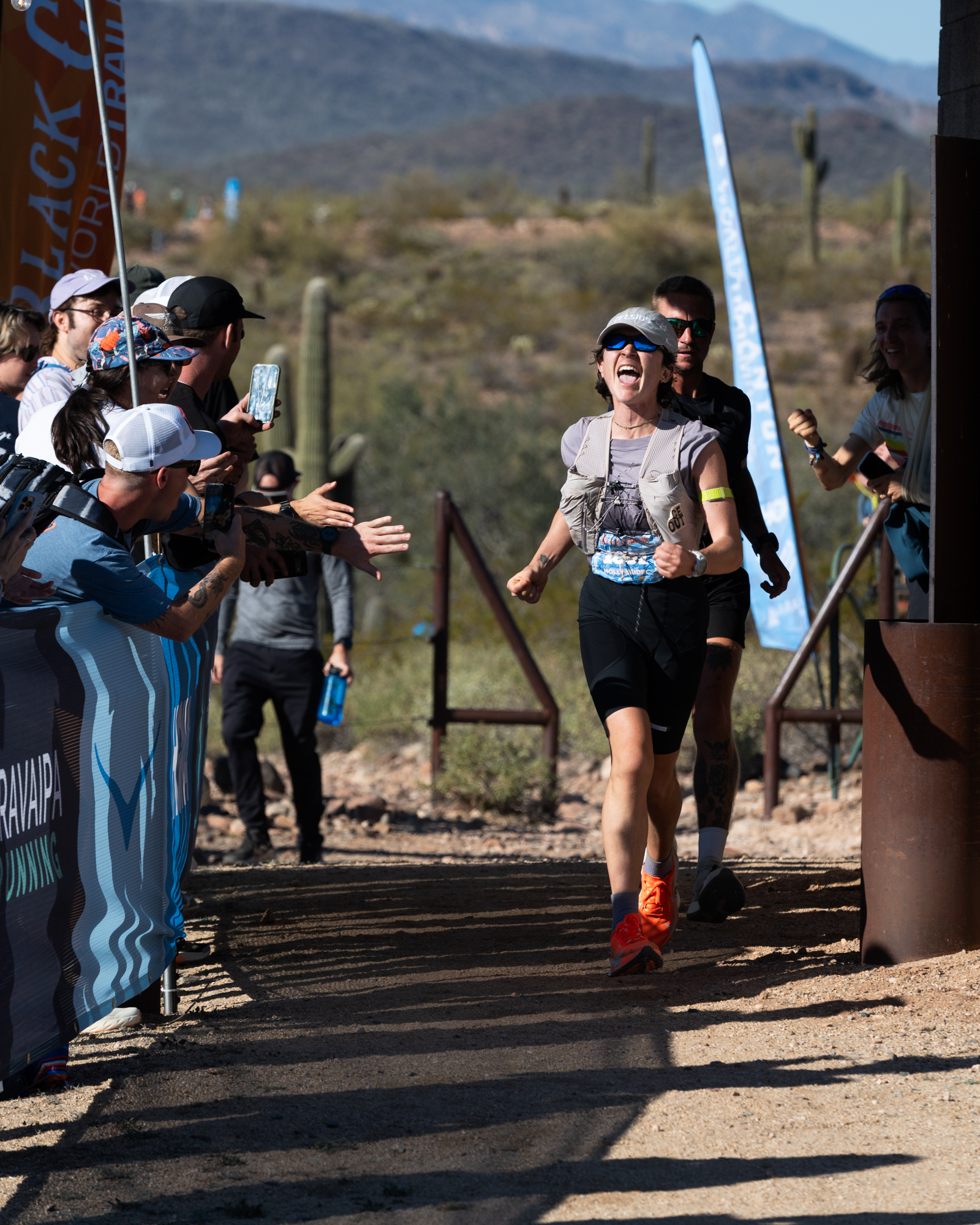 Runner smiling and high-fiving supporters at a finish line.