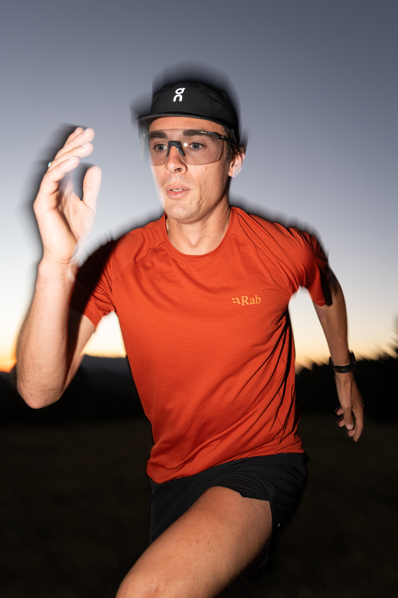 Runner in an orange technical shirt moving through evening light.